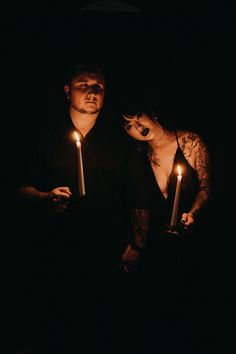 two people standing in the dark holding candles