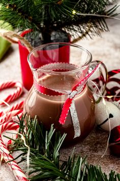 a glass pitcher filled with hot chocolate surrounded by candy canes