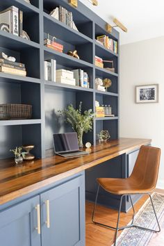 an office with blue bookcases and a wooden desk in front of the bookshelf