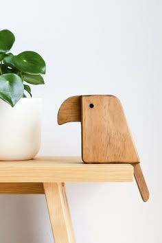 a potted plant sitting on top of a wooden shelf next to a white vase