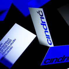 some blue and white business cards sitting on top of each other in front of a black background