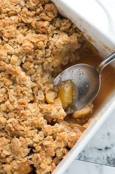 a casserole dish filled with apple crumbled toppings and a spoon