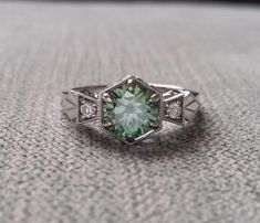 a ring with a green stone in the center and two white diamonds on each side