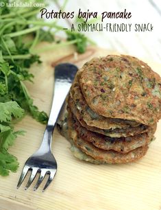 a stack of potato pancakes sitting on top of a wooden cutting board next to a fork