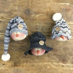 three small stuffed animals wearing hats on top of a wooden table