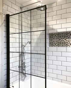 a white tiled bathroom with black trim and glass shower door, along with a bathtub in the corner