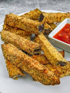 some fried food on a white plate next to a small bowl of tomato dipping sauce