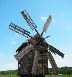 an old wooden windmill sitting in the middle of a field