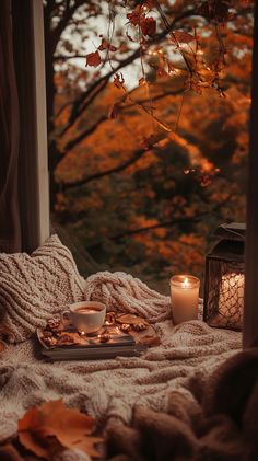 a candle and some food on a blanket by a window with trees in the background