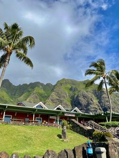 palm trees are in the foreground and mountains in the background, with a building on the far side