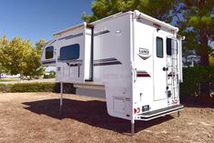 an rv parked in the dirt near some trees