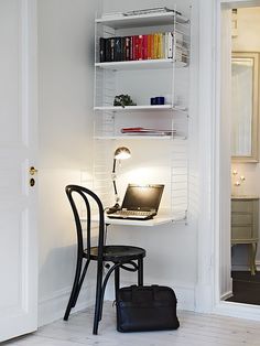 an image of a small room with a laptop on the desk and a chair next to it