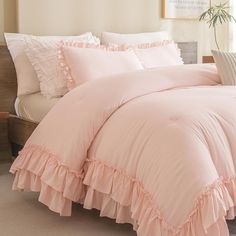 a pink comforter with ruffled edges and pillows