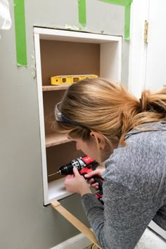 a woman is drilling holes in the wall