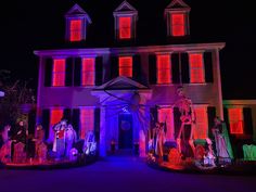 a large house with halloween decorations on the front and side windows lit up at night