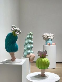 three ceramic sculptures on pedestals in an art gallery