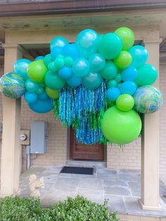 a bunch of blue and green balloons hanging from the side of a building