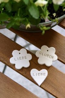 two small white hearts sitting on top of a wooden bench next to a potted plant