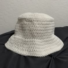 a white crocheted hat sitting on top of a black cloth covered tablecloth