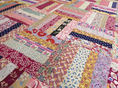 a large patchwork quilt with many different colors and patterns on the fabric, including pinks, purples, yellows and blue