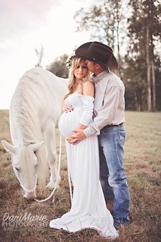 a pregnant woman in a white dress and cowboy hat standing next to a man with a horse