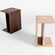 two small wooden tables sitting next to each other on a white surface in front of one another