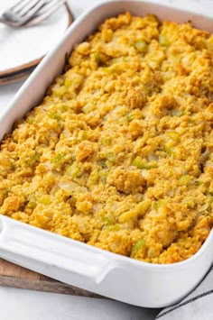 a casserole dish filled with stuffing sitting on top of a wooden cutting board