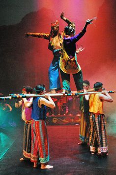 people are performing on stage with sticks in the air