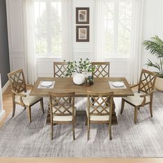 a dining room table and chairs in front of two windows with potted plants on them