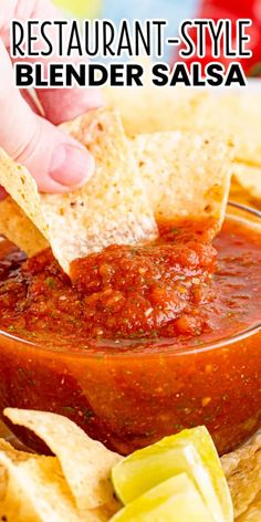 a person dipping salsa into a bowl with tortilla chips