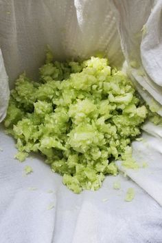 a bag filled with green food sitting on top of a white cloth covered tablecloth