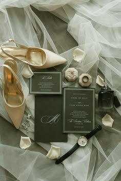 wedding stationery and accessories laid out on a bed with tulle, watch, ring, watch wind chime