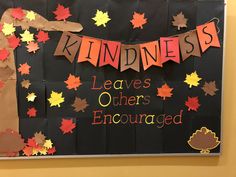 a bulletin board with leaves on it and the words kindness spelled in red, orange, and yellow