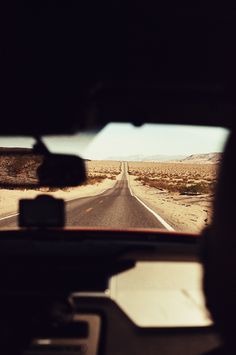 the view from inside a vehicle looking at an empty road in the middle of nowhere