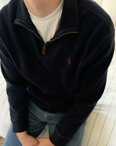 a young man sitting on top of a white couch wearing a black jacket and jeans