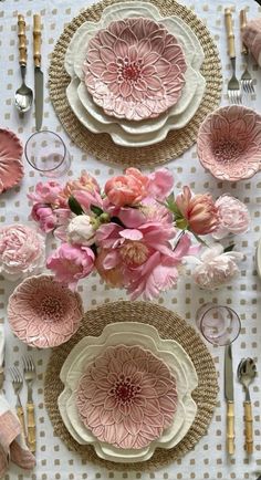 the table is set with pink flowers and plates