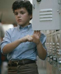 a young boy is holding up a box in front of lockers that are filled with keys