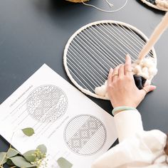 a woman is knitting on the table next to some yarn and crochet hooks