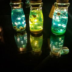 three glass jars with lights in them are sitting on a black surface and one is empty