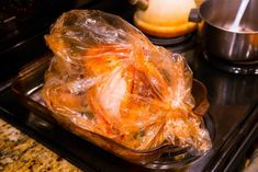 a turkey wrapped in plastic sitting on top of a stove