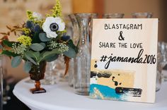 a table topped with vases filled with flowers next to a sign that says blasatagram and share the love