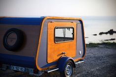 an orange and blue trailer parked next to the ocean