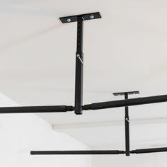 an overhead pull up bar in a room with white walls and black metal bars hanging from the ceiling