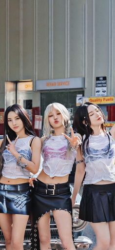 three young women standing next to each other in front of a gas station with their hands on their hips