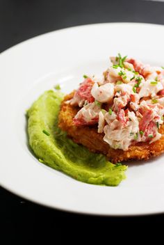 a white plate topped with food on top of a green substance covered in toppings