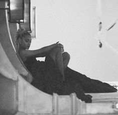 black and white photograph of a woman sitting on the ground looking at her cell phone