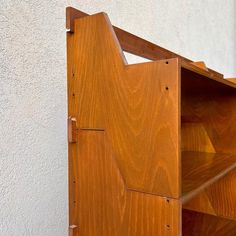 a wooden book shelf sitting next to a white wall