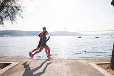 a man and woman running near the water