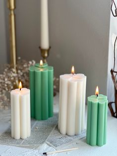 four candles are lined up on a table next to a candle holder and some scissors