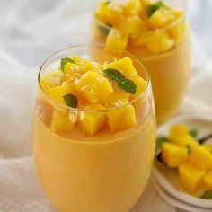 two glasses filled with fruit and garnished with mint on the rim, sitting on a white cloth